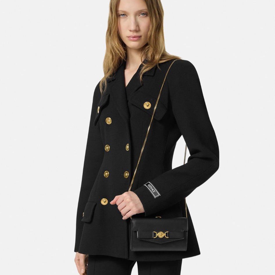 Woman wearing a black coat with gold buttons on a white background