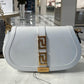 White handbag with gold accents on a marble surface in a store setting