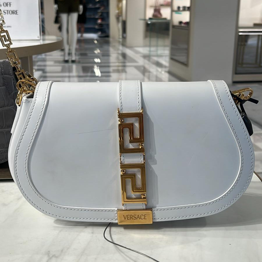 White handbag with gold accents on a marble surface in a store setting