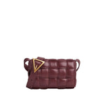 Maroon woven handbag with a gold triangle accent on a light gray background