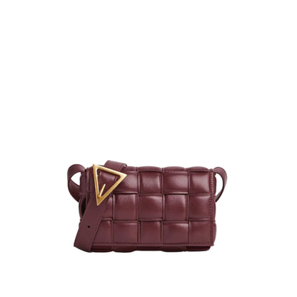 Maroon woven handbag with a gold triangle accent on a light gray background
