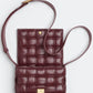 Brown quilted leather crossbody bag on a light gray background