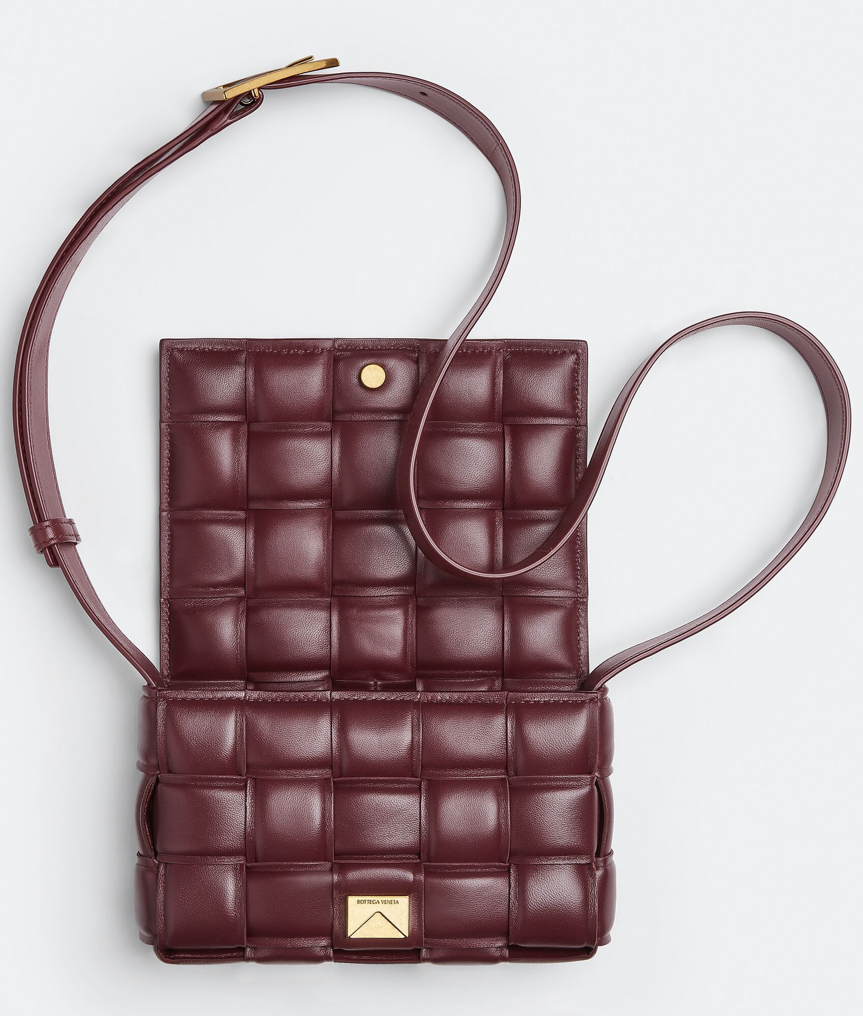 Brown quilted leather crossbody bag on a light gray background