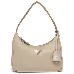 A beige Prada shoulder bag with a curved top, a single shoulder strap, a zippered top closure, and a hanging leather tag on a white background.