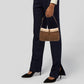 Person holding a brown handbag with a plain background