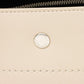 Close-up of a beige leather product with a silver brand logo and stitching detail.