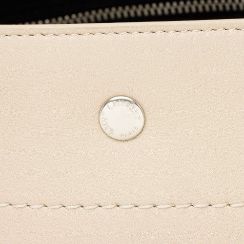 Close-up of a beige leather product with a silver brand logo and stitching detail.