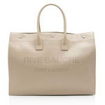 Beige handbag with 'Rive Gauche Saint Laurent' branding on a white background
