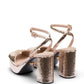 Pair of gold sequin high-heeled shoes on a white background