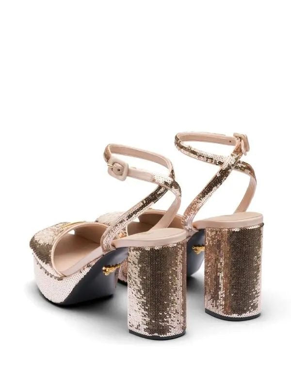Pair of gold sequin high-heeled shoes on a white background