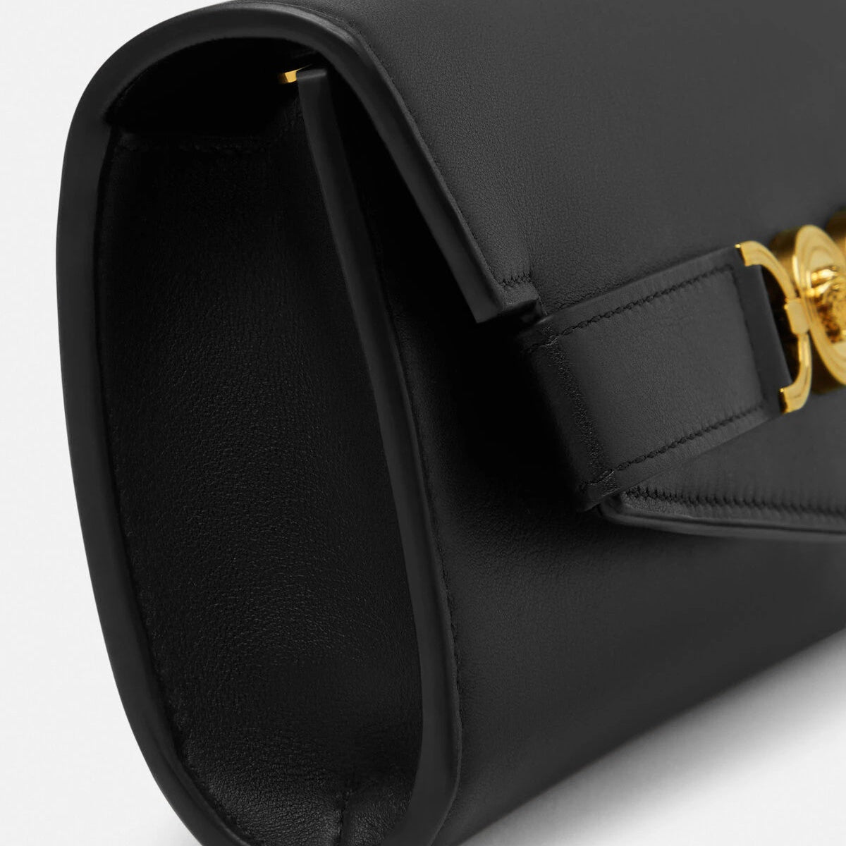 Black handbag with a gold clasp on a light gray background