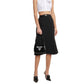 Person wearing a white sleeveless top and black Prada skirt on a white background