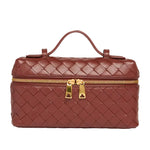 Brown woven handbag with gold zipper and handle on a white background