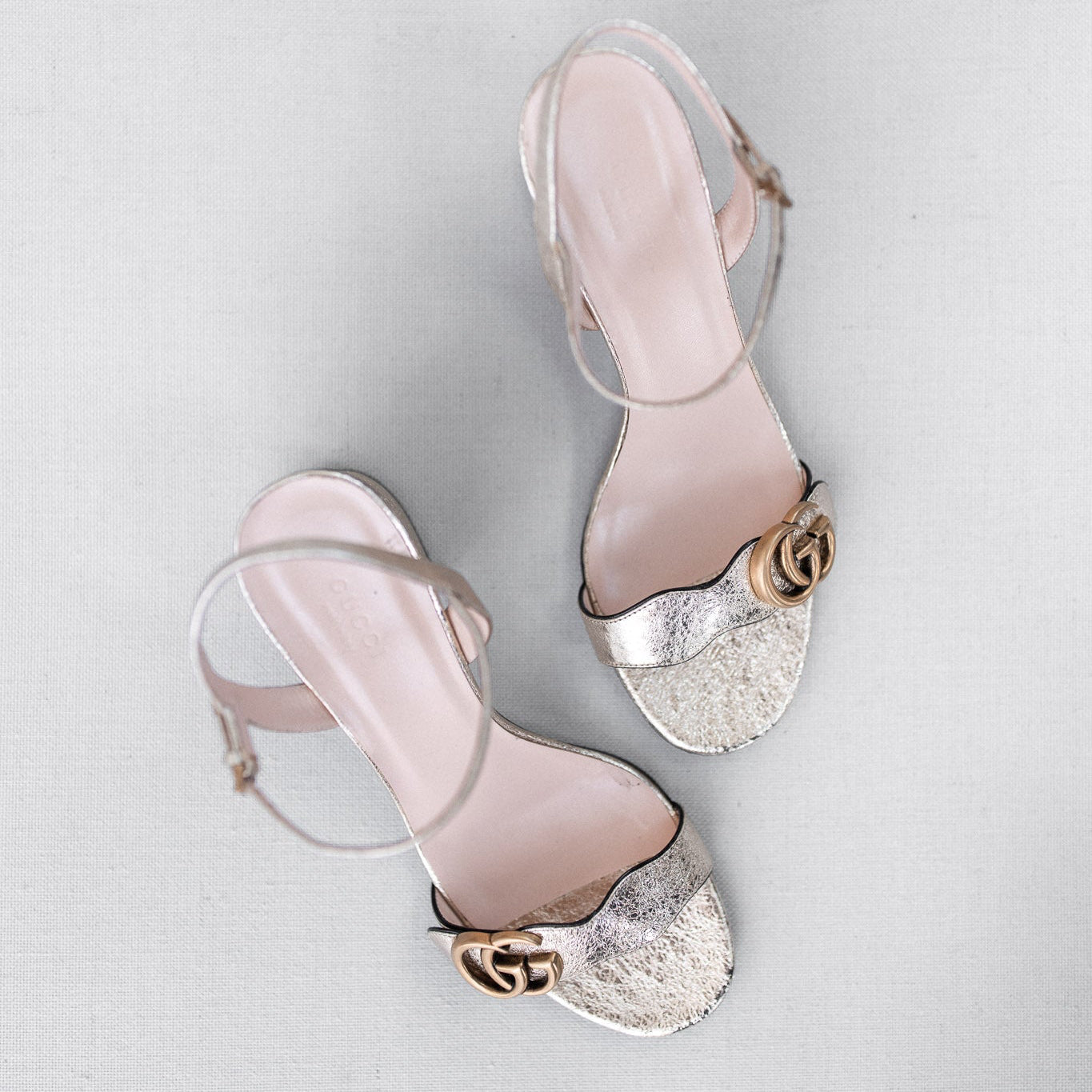 Pair of pink high-heeled sandals with glittery platforms on a light gray background