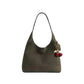Green handbag with a cherry charm on a light gray background