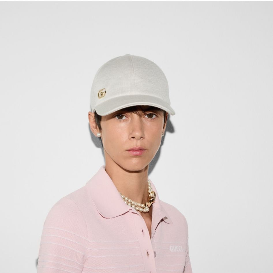 Person wearing a white cap and pink shirt on a plain background