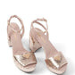 Pair of pink high-heeled sandals with sequin details on a white background