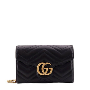 Black quilted handbag with gold chain and logo on a white background