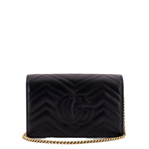 Black quilted handbag with gold chain on a white background