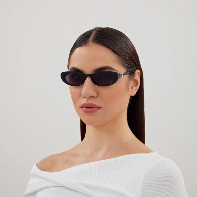 Woman wearing black sunglasses against a plain background