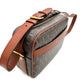 Designer handbag with brown leather strap and monogram pattern on a white background